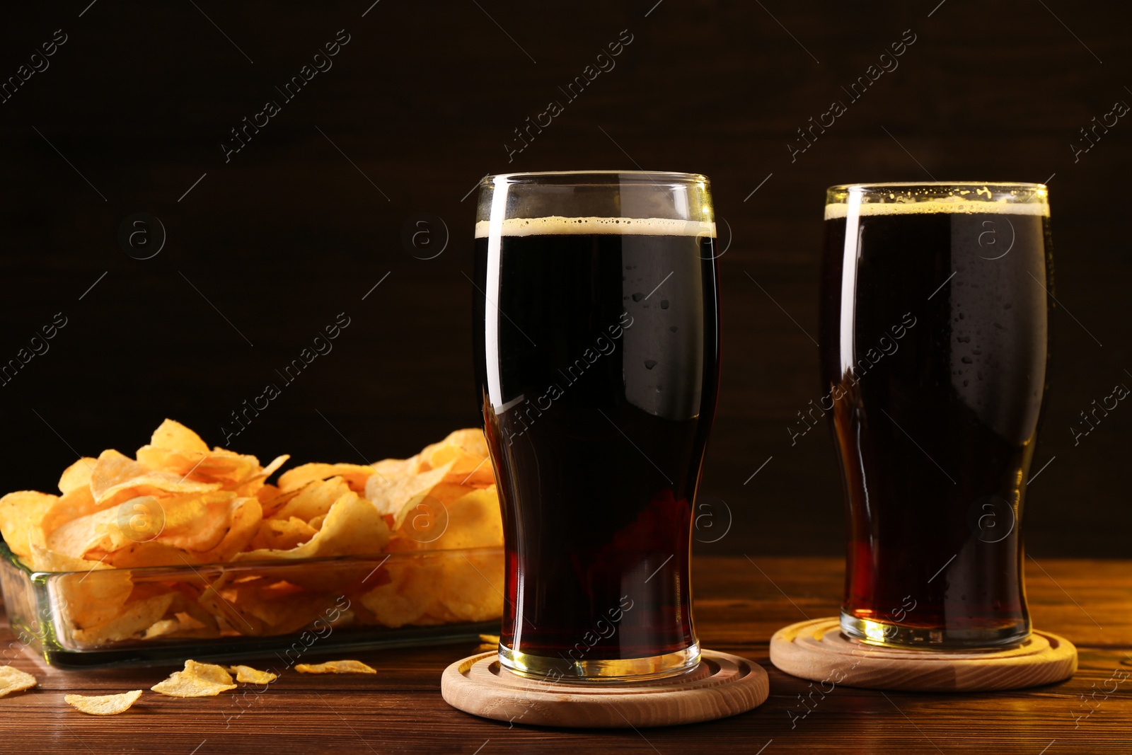 Photo of Glasses of beer and potato chips on wooden table