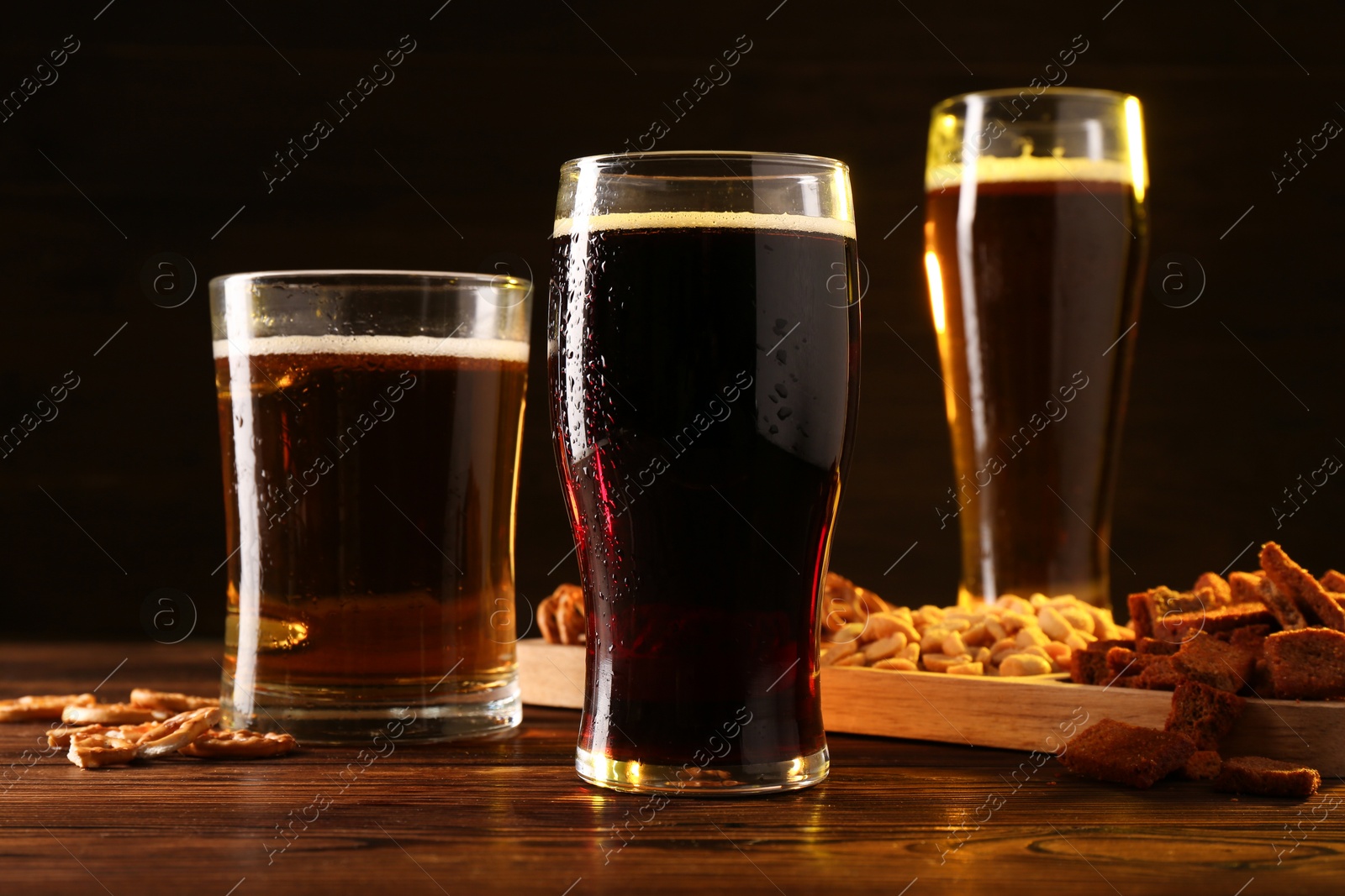 Photo of Glasses with different types of beer and snacks on wooden table