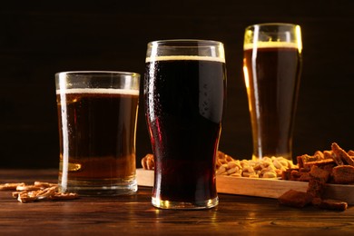 Glasses with different types of beer and snacks on wooden table