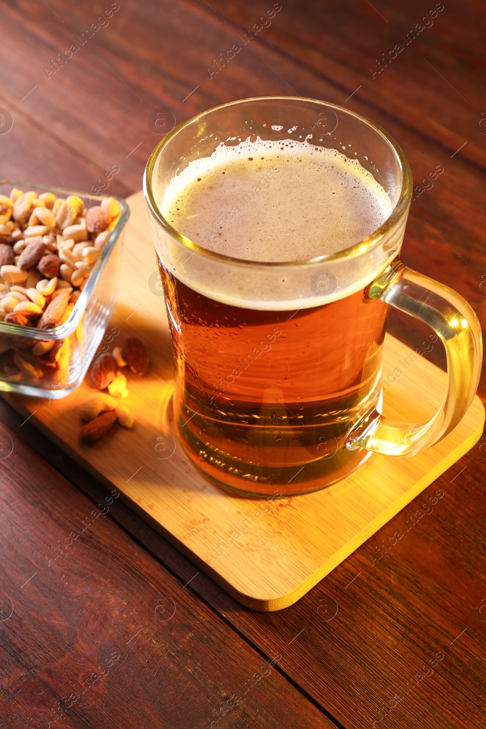 Photo of Glass mug of beer and nuts on wooden table