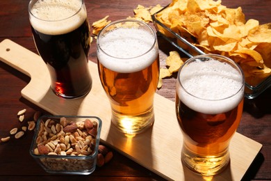 Photo of Glasses of beer and snacks on wooden table