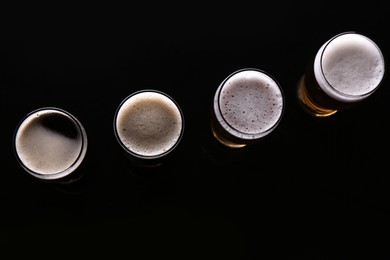 Photo of Glasses with different types of beer on black background, flat lay