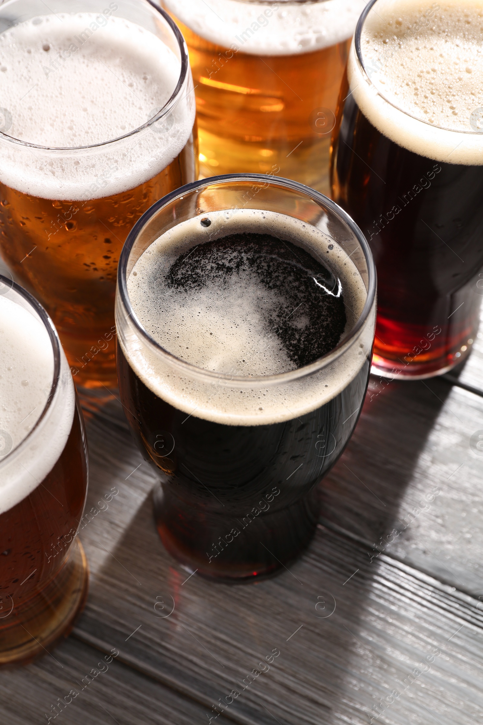 Photo of Glasses with different types of beer on grey wooden table