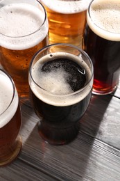 Photo of Glasses with different types of beer on grey wooden table