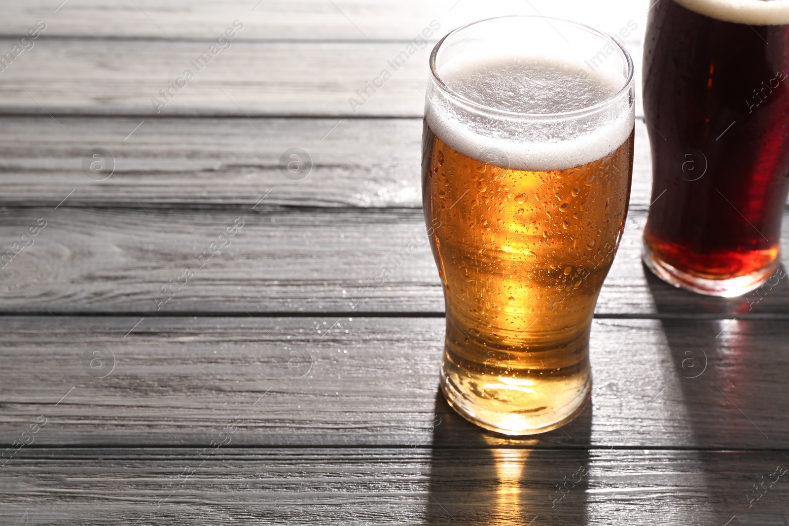 Photo of Glasses with different types of beer on grey wooden table, space for text