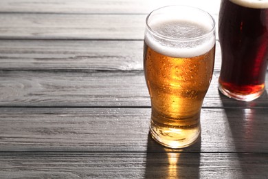 Glasses with different types of beer on grey wooden table, space for text