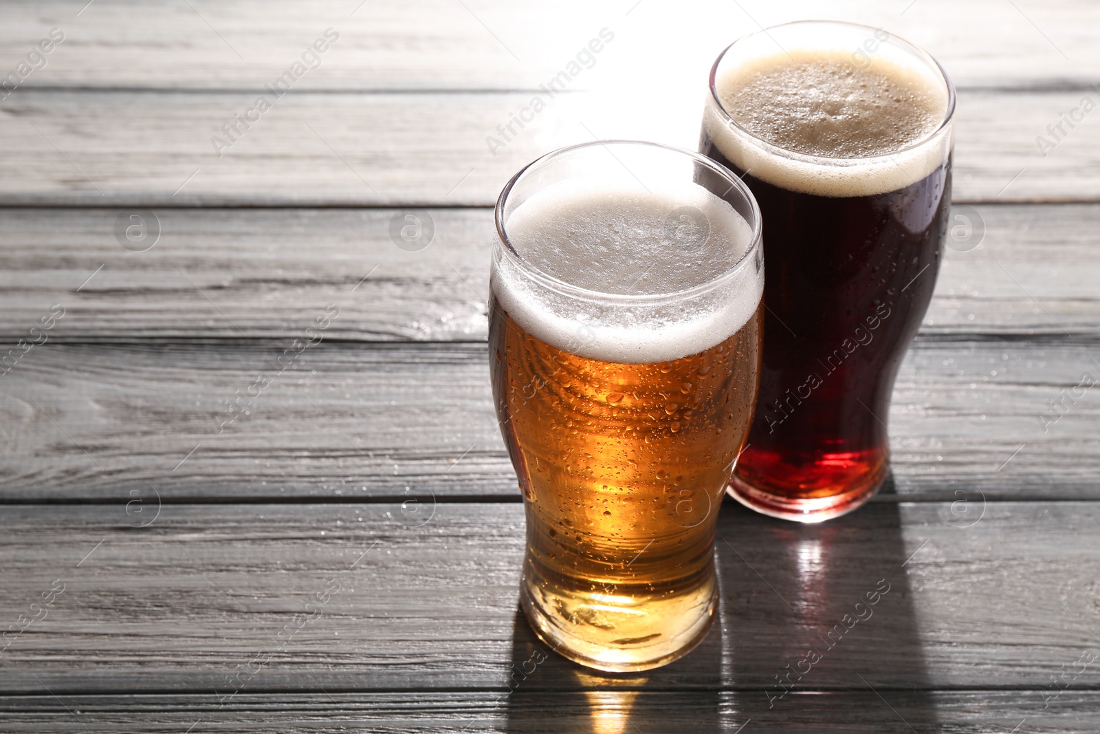 Photo of Glasses with different types of beer on grey wooden table, space for text