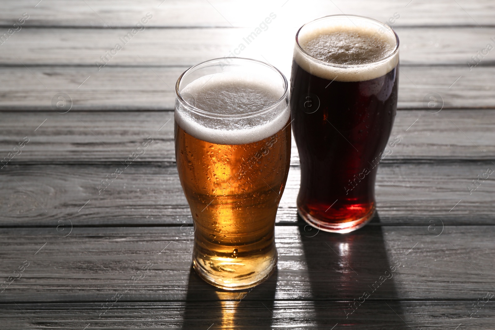 Photo of Glasses with different types of beer on grey wooden table