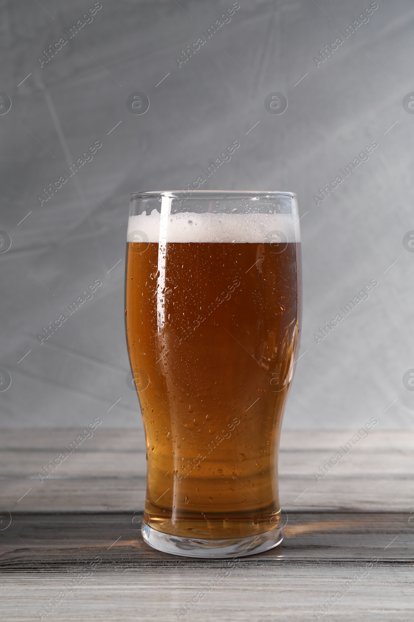 Photo of Glass of beer on grey wooden table