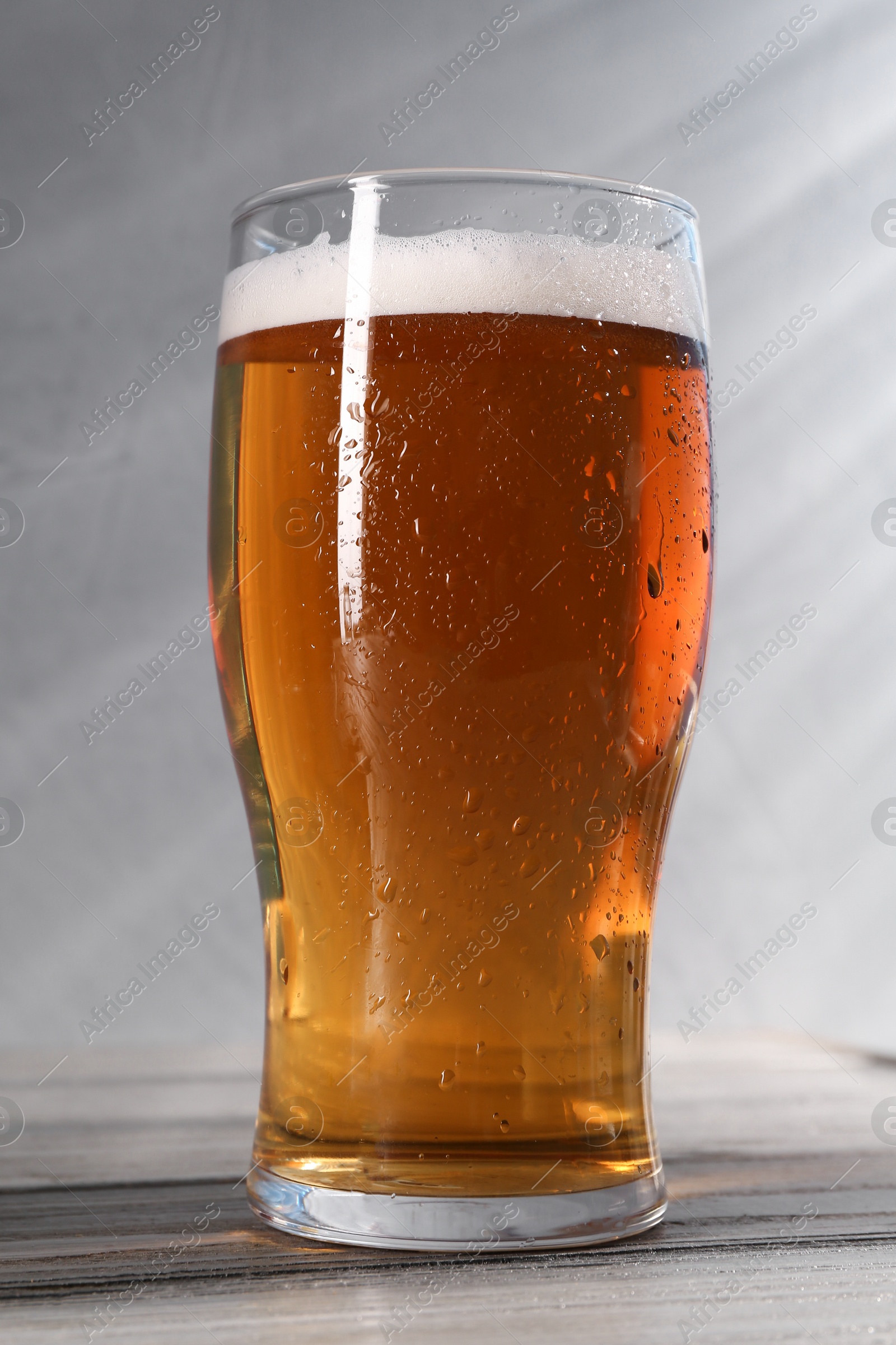 Photo of Glass of beer on grey wooden table