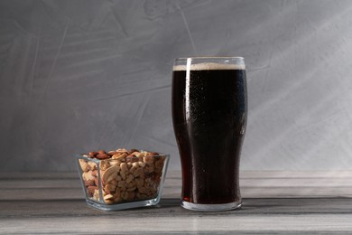 Photo of Glass of beer and nuts on grey wooden table