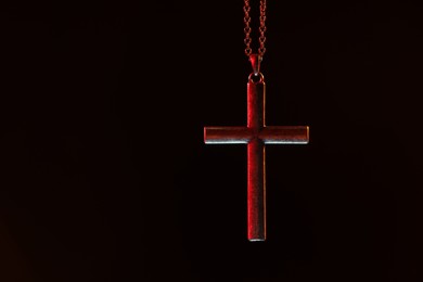 One cross with chain on black background, space for text. Religion of Christianity