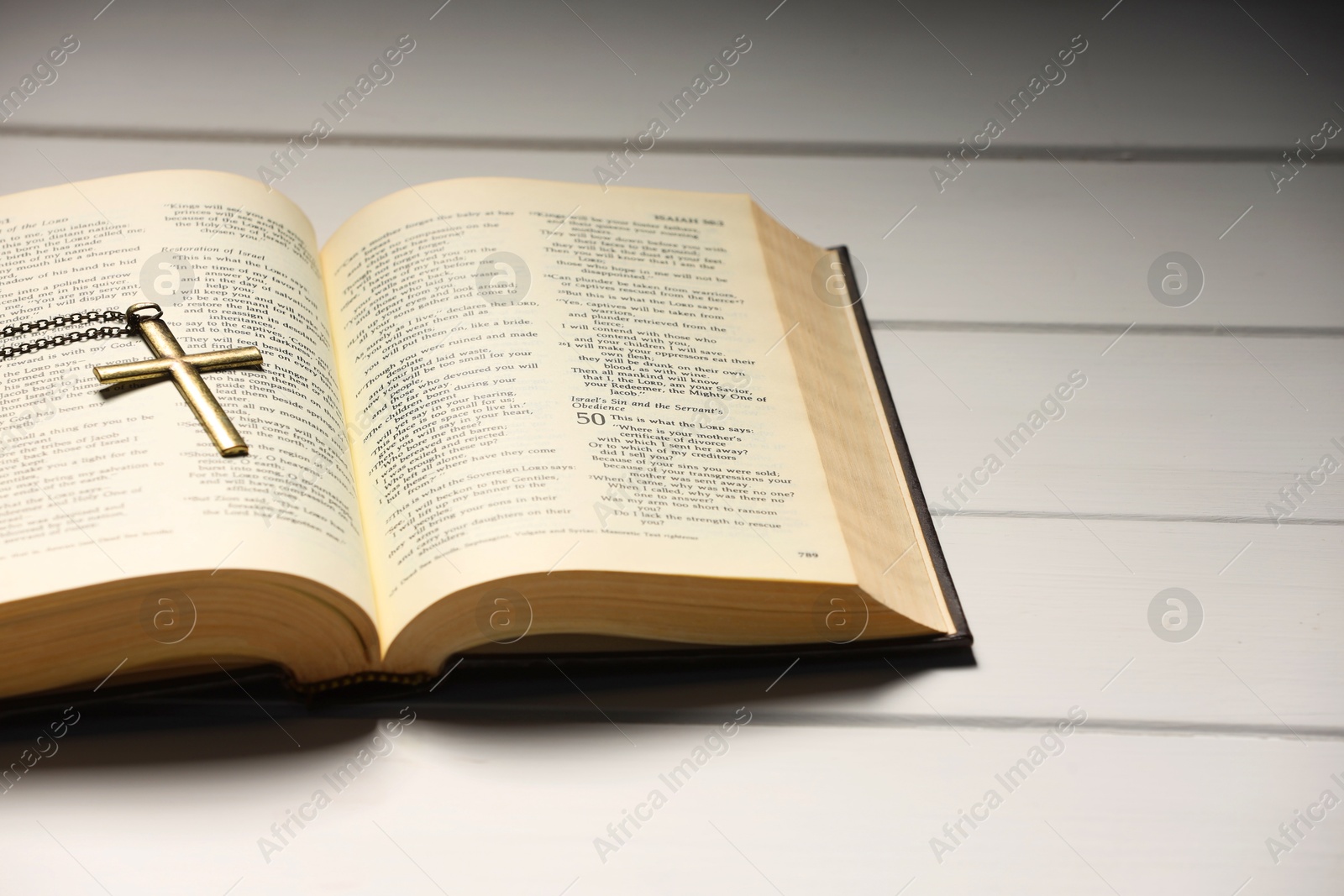 Photo of Cross with chain and Bible on white wooden table, closeup with space for text. Religion of Christianity