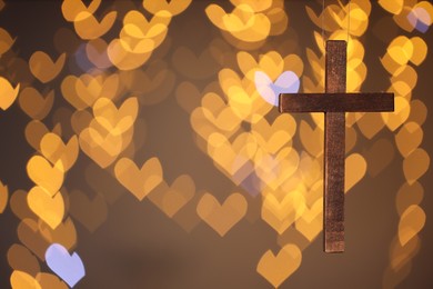 Wooden cross against blurred lights, closeup with space for text. Religion of Christianity