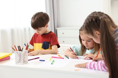 Photo of Group of children drawing at table indoors