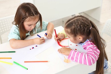 Photo of Cute little children drawing at table indoors