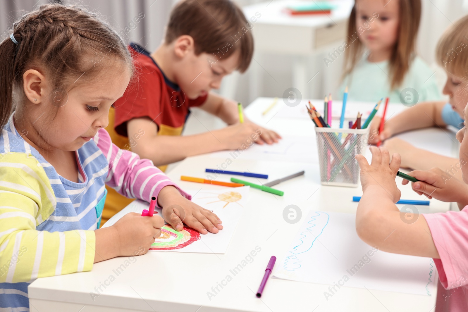 Photo of Group of children drawing at table indoors