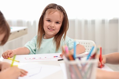 Cute little children drawing at table indoors