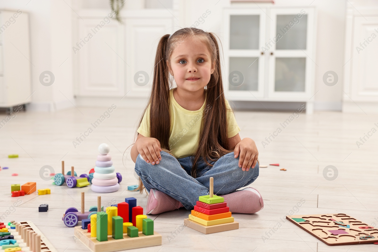 Photo of Cute little girl playing on floor indoors