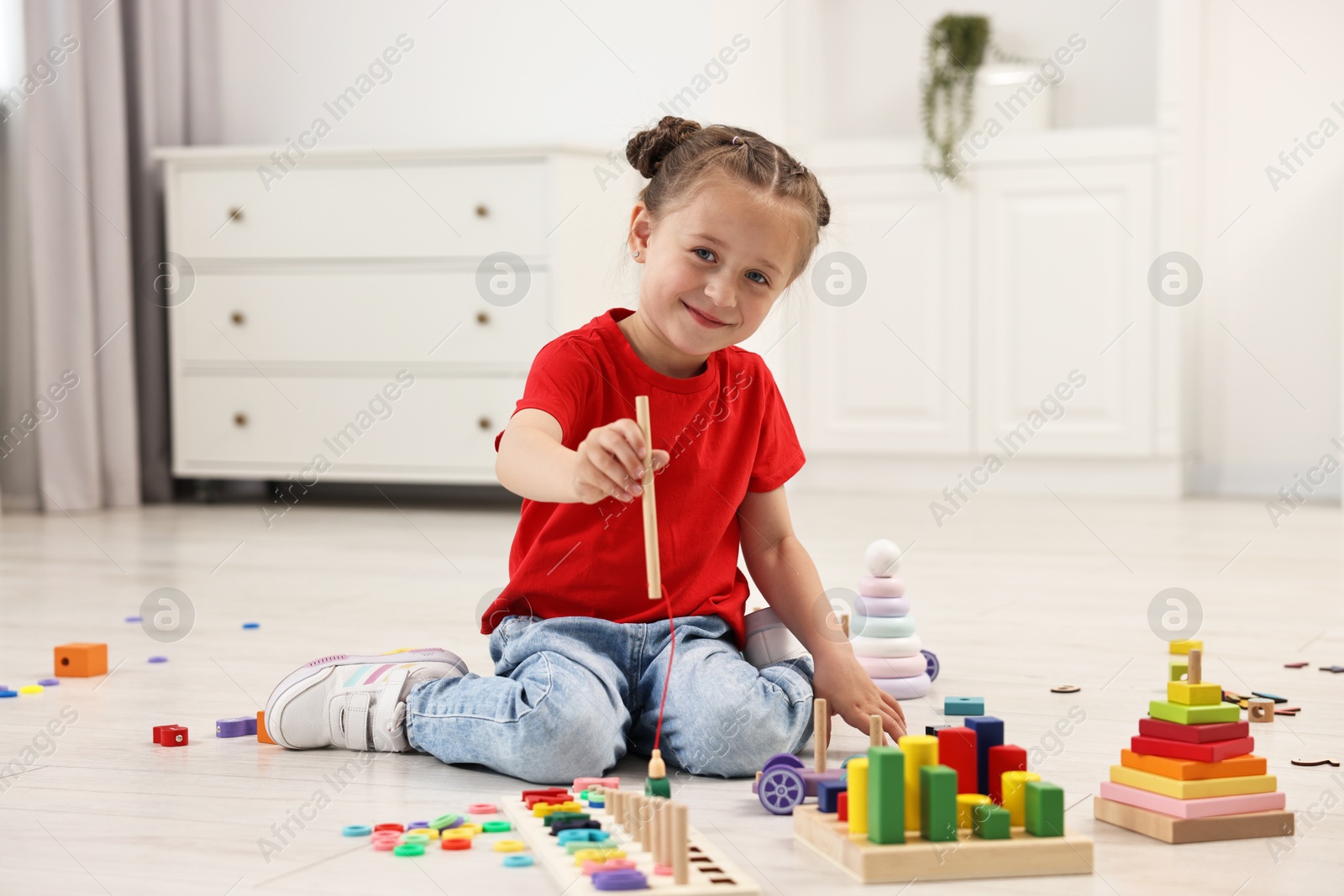 Photo of Cute little girl playing with math game Fishing for Numbers on floor indoors