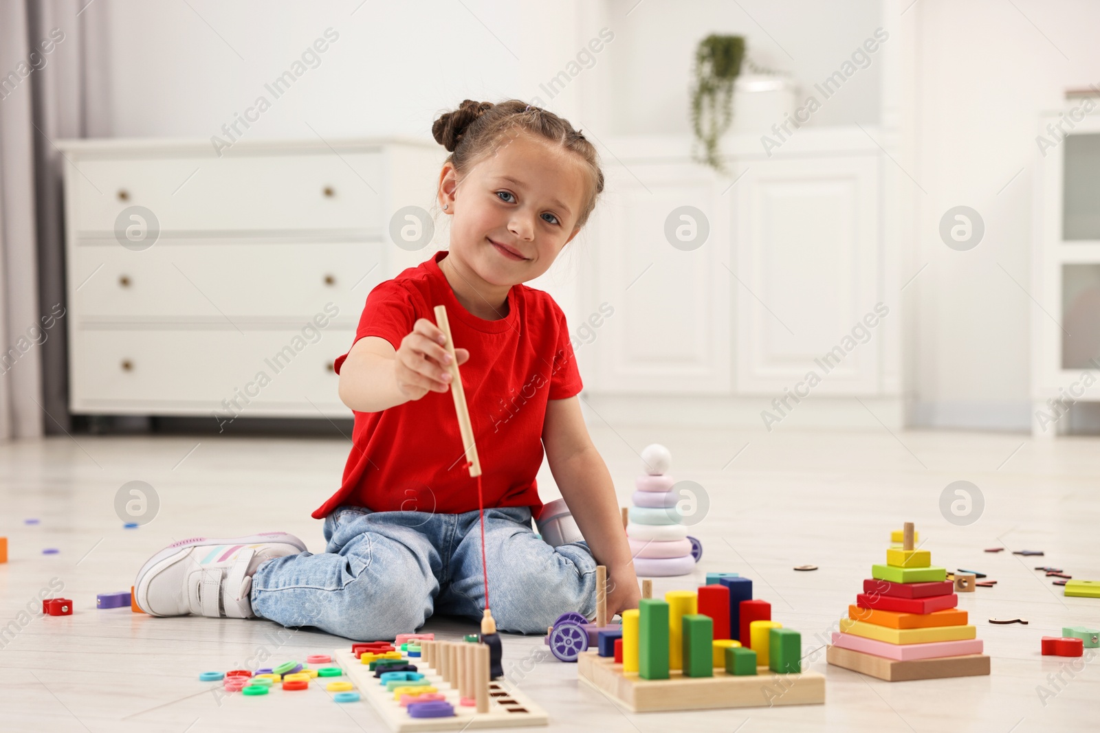 Photo of Cute little girl playing with math game Fishing for Numbers on floor indoors