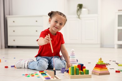 Cute little girl playing with math game Fishing for Numbers on floor indoors