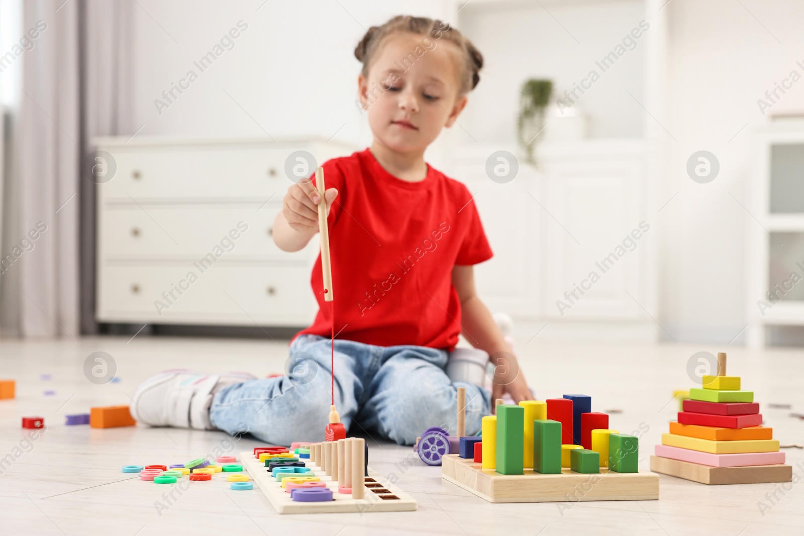 Photo of Cute little girl playing with math game Fishing for Numbers on floor indoors