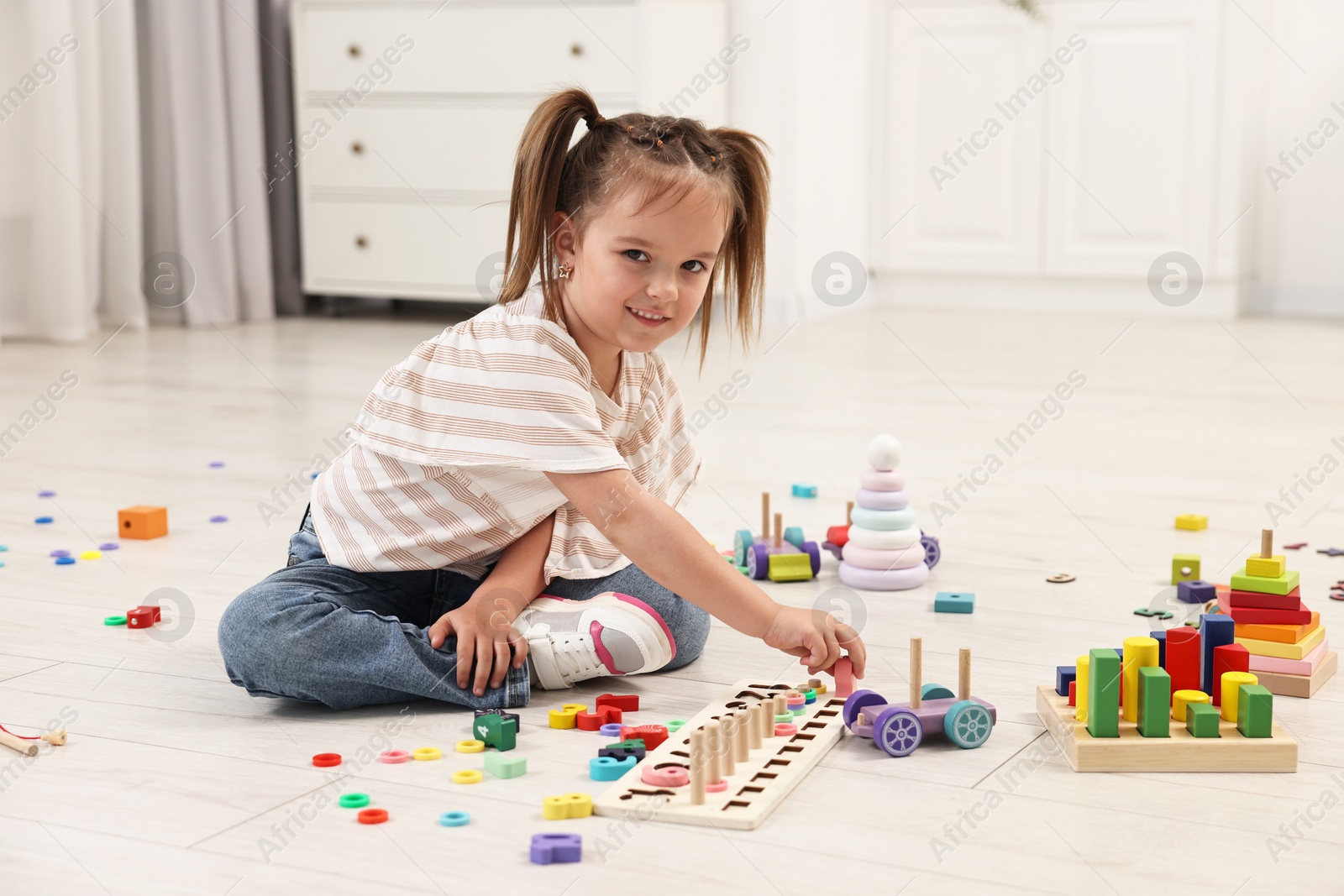 Photo of Cute little girl playing with math game Fishing for Numbers on floor indoors