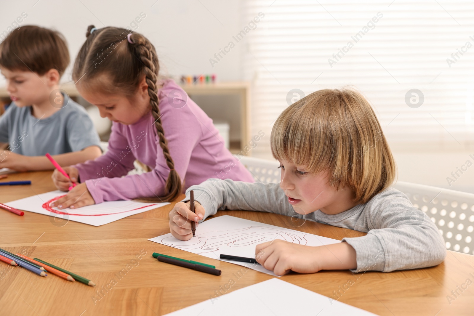 Photo of Cute little children drawing at wooden table indoors