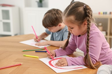 Photo of Cute little children drawing at wooden table indoors