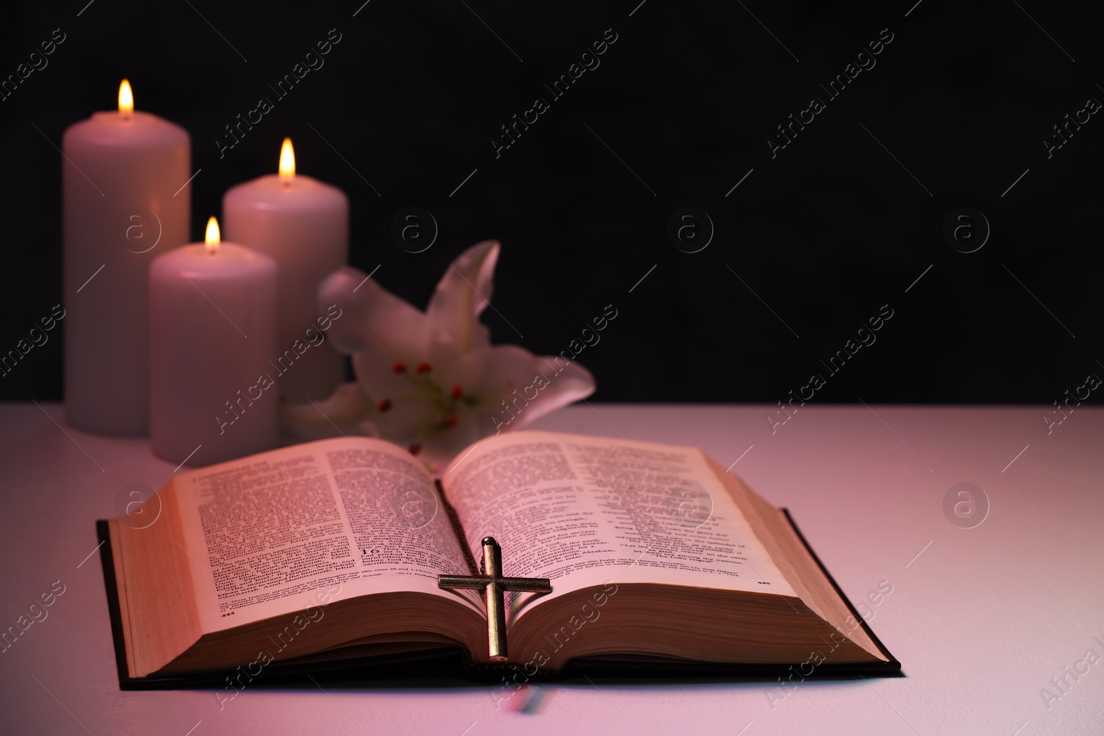 Photo of Cross, Bible, flower and burning candles on textured table against black background, space for text. Religion of Christianity