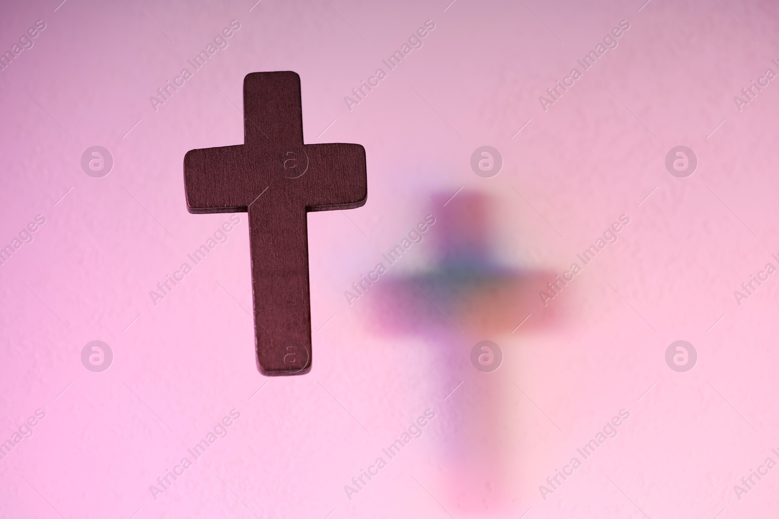 Photo of Wooden cross on pink textured background, space for text. Religion of Christianity