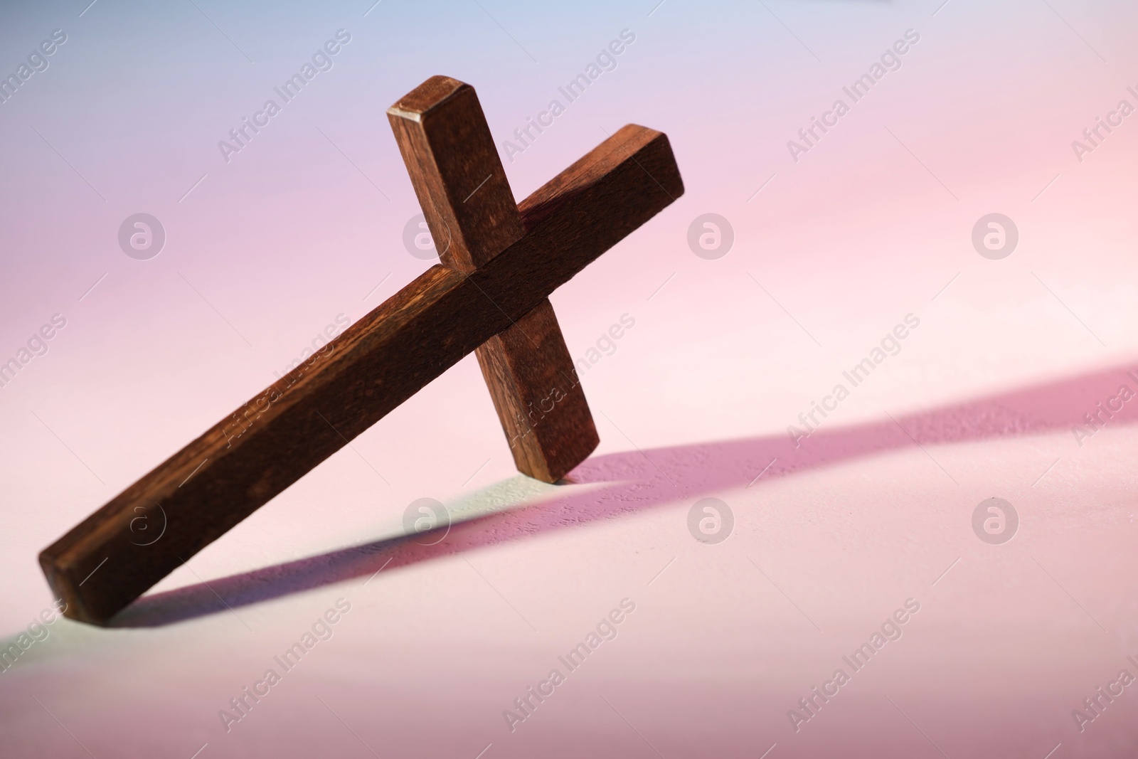 Photo of Wooden cross on textured table in color lights, closeup with space for text. Religion of Christianity