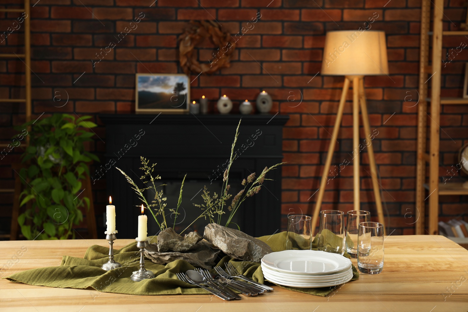 Photo of Clean dishes, stones and plants on wooden table in stylish dining room