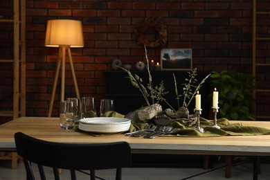 Clean dishes, stones and plants on wooden table in stylish dining room