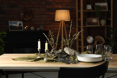 Photo of Clean dishes, stones and plants on wooden table in stylish dining room