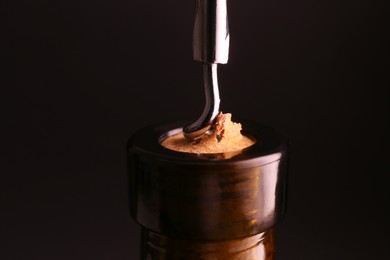 Wine bottle with corkscrew on dark background, closeup