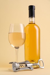 Photo of Wing corkscrew, bottle and glass of wine on beige background