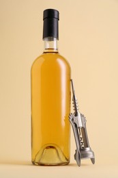 Wing corkscrew and bottle of wine on beige background