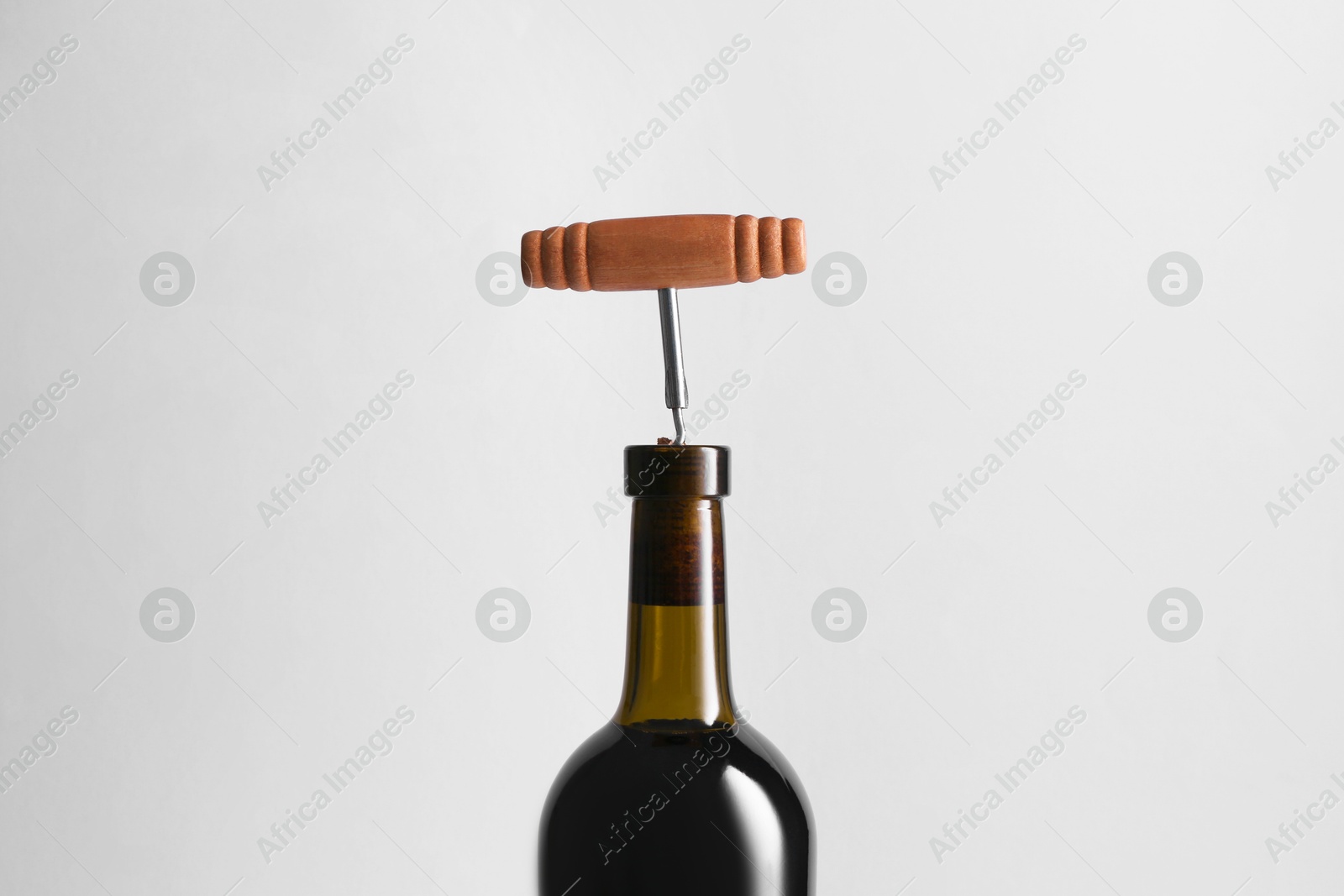 Photo of Wine bottle with corkscrew on light grey background