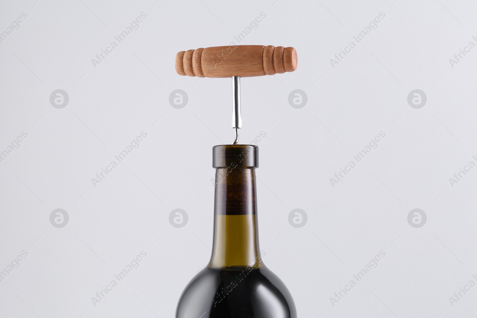 Photo of Wine bottle with corkscrew on light grey background