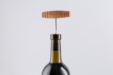 Wine bottle with corkscrew on light grey background