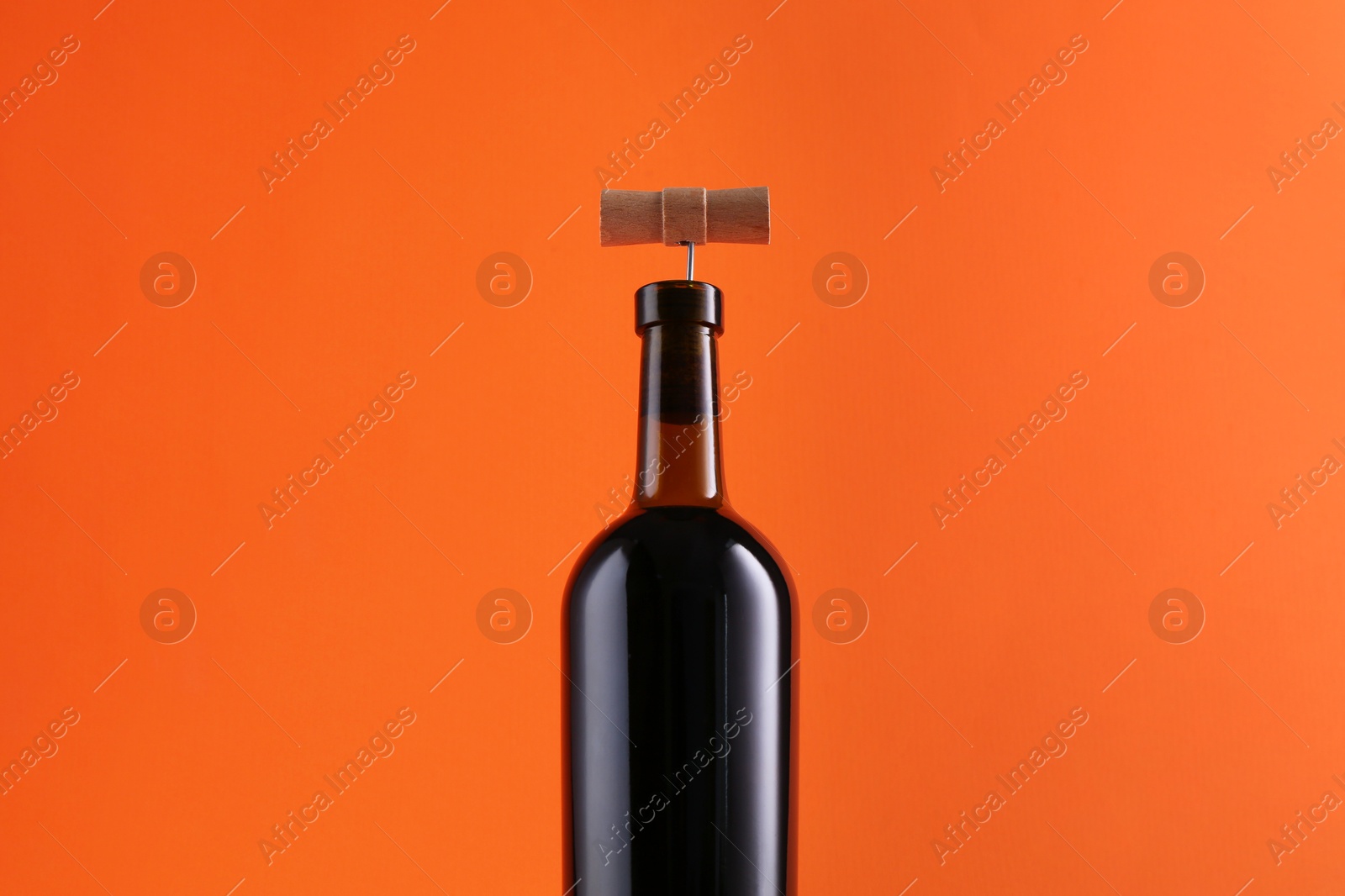 Photo of Wine bottle with corkscrew on orange background