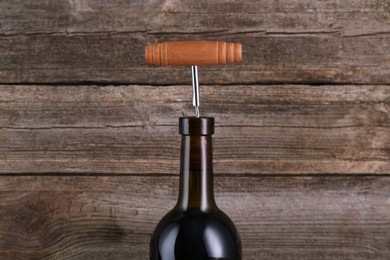 Wine bottle with corkscrew on wooden background