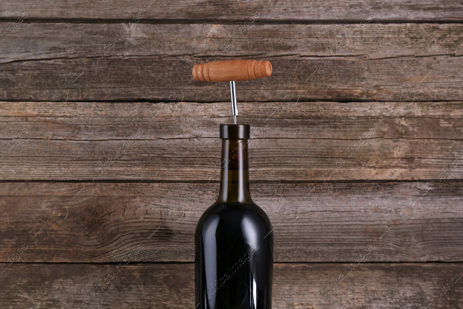 Photo of Wine bottle with corkscrew on wooden background