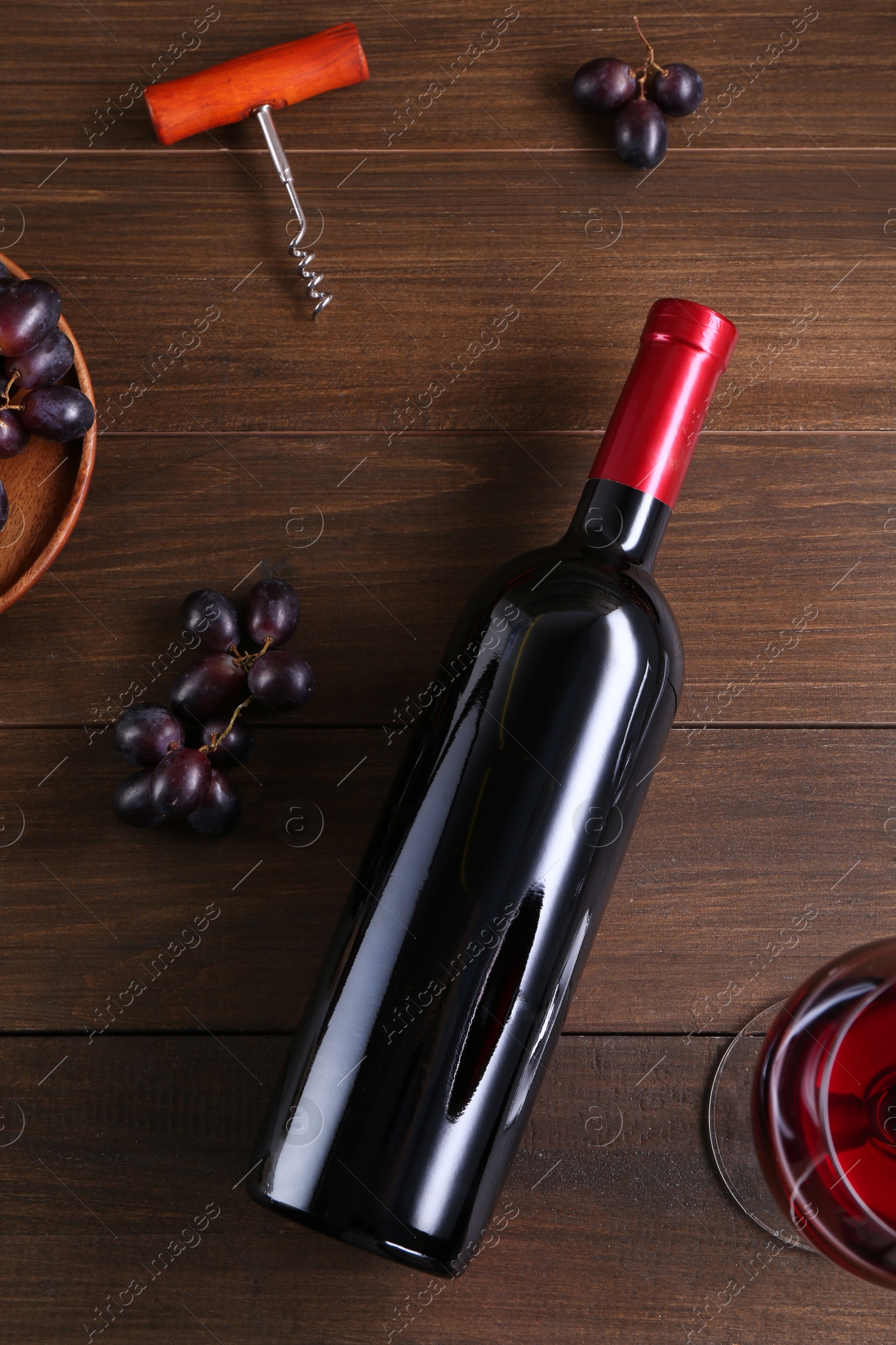 Photo of Flat lay composition with corkscrew and red wine on wooden table