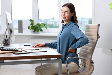 Photo of Woman suffering from back pain in office. Symptom of poor posture