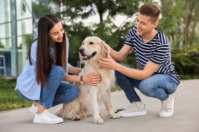 Photo of Happy couple with cute Golden Retriever dog outdoors