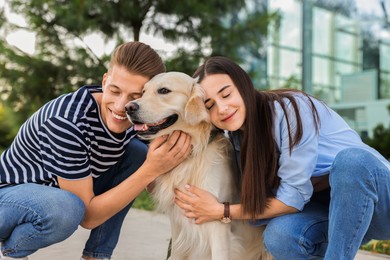 Happy couple with cute Golden Retriever dog outdoors