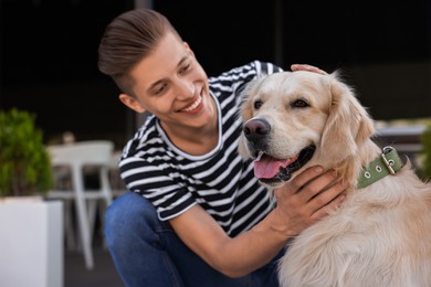 Photo of Happy owner stroking cute Golden Retriever dog outdoors